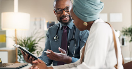 Tablet, checkup and black woman with doctor in clinic for medical diagnosis or wellness advice. Discussion, digital technology and female patient with healthcare worker for consultation in hospital.の写真素材