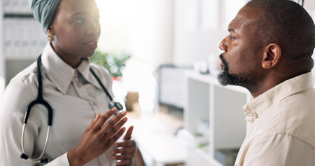 Doctor, patient and talking in clinic for consultation, healthcare and procedure for examination. Black people, man and stress in practice with medical service, discussion and help with diagnosisの写真素材