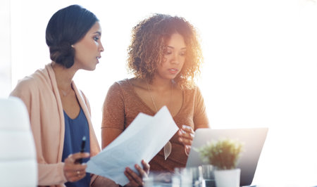 Business women, paperwork and laptop with meeting and seo research for content creation update. Office, digital work and management of company website with discussion and collaboration with mockupの写真素材