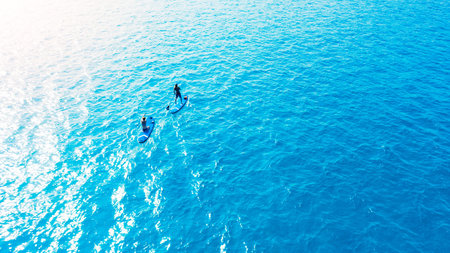 Couple, paddle board and ocean on vacation, above and together for exercise, nature and sunshine for adventure. People, man and woman in summer with fun in tropical water, journey or sea in Malaysiaの写真素材