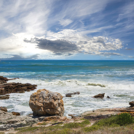 Rocks, beach and sea coast for travel, holiday or vacation in nature with clouds outdoor. Ocean water, stones or waves in horizon with grass for tourism, adventure island or environment in Californiaの写真素材