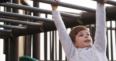 Boy, child and monkey bars at playground, outdoor and adventure with smile, learning and balance. Kid, happy and exercise with swing on jungle gym at park for challenge, climbing or sunshine in Spainの写真素材