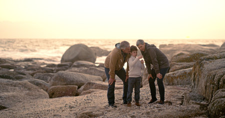 Happy, ocean and grandparents with child explore for bonding, fun weekend and relax together at beach. Nature, family and young boy, grandpa and grandma on holiday, adventure and vacation togetherの写真素材