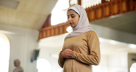 Muslim, prayer and religion with woman in mosque to praise or worship Allah for ramadan. Hajj, hijab and Islam with Arabic person praying at temple for belief, culture or faith in Middle Eastの写真素材