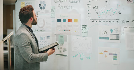 Planning, tablet or whiteboard and business man in office with graphs of company growth strategy. Brainstorming, data and research with professional employee in workplace for goals or targetの写真素材