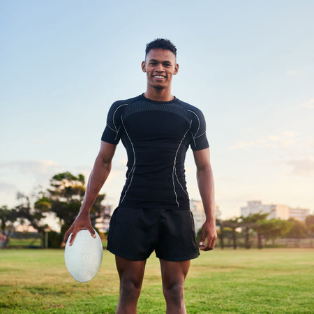 Outdoor, portrait and man with ball, rugby and confident for match, stadium and fitness of player with smile. Playground, proud and training for competition, field and skill for sport and personの写真素材