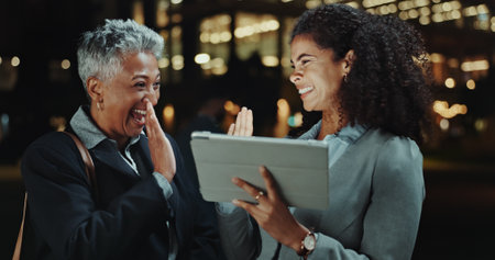 City, high five and colleagues with tablet, night and happy for deal, trader and joy for opportunity. Achievement, office and win for investment banker, celebration and success for corporate peopleの写真素材