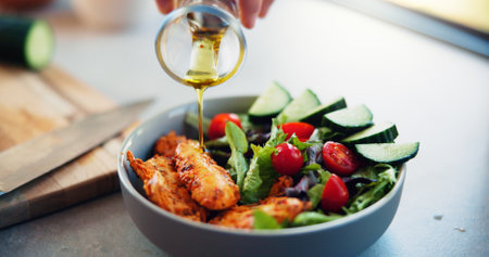 Hands, olive oil and salad in kitchen, home and meal prep with seasoning, meat or flavor with vegetables. Person, chef and bowl with food for nutrition, wellness or gut health with diet at apartmentの写真素材