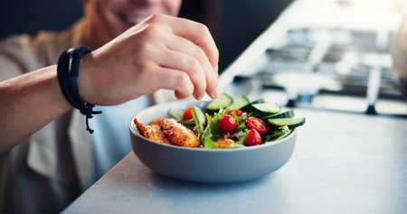 Hands, seasoning and salad in kitchen, home and meal prep with spice, herbs or flavor with vegetables. Person, chef and bowl with food for nutrition, wellness or gut health with organic diet in houseの写真素材