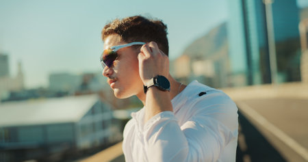 Fitness, earbuds and man in city, workout and runner with audio, listening to music and exercise. New York, person and athlete in street, sunglasses and training with radio and podcast for motivationの写真素材