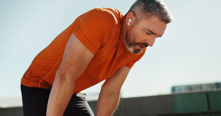 Fitness, tired and man in city, sports and exhausted with challenge, workout and break. Mature person, outdoor and runner with exercise, training or health with fatigue, relax or athlete with routineの写真素材