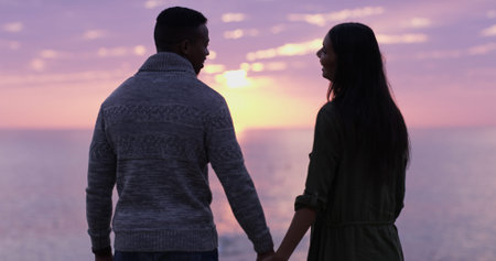 Sunset, beach and couple holding hands on holiday date, romantic adventure or sightseeing from back....