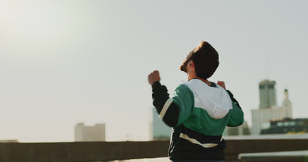 Celebration, back and runner in morning, fitness and practice for marathon, success and mockup space. Sky, fist and accomplishment for routine, exercise and person in city, healthy and victoryの写真素材