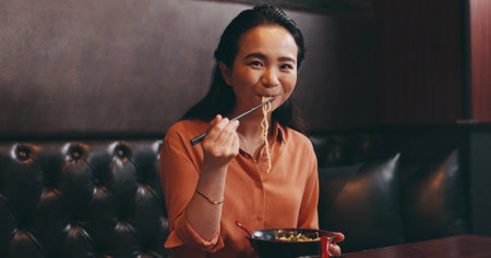 Woman, portrait and eating noodles in Japan, food and nutrition in dinner dish at restaurant. Female person, traditional cuisine and customer at bistro with meal, ramen culture and gourmet dietの写真素材