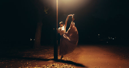 Ballet, dance and lamp with Japanese woman in city for balance, theater and elegant performance. Talent, art and feminine with person or ballerina dancer at night for recital, music or practiceの写真素材