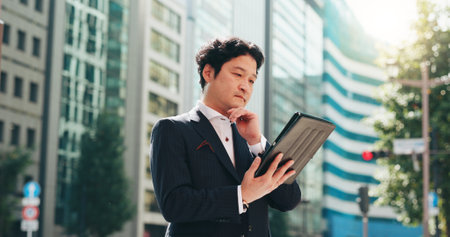 Man, thinking and tablet in city for business, travel and research for urban development in Osaka. Mature investor, tech or reading in Japanese town for news, investment opportunity or economy growthの写真素材