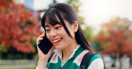 Japan, phone call and outdoor with woman, smile and communication with contact. Happy, person and student with smartphone, mobile user and technology with digital app, commute and joyful in parkの写真素材