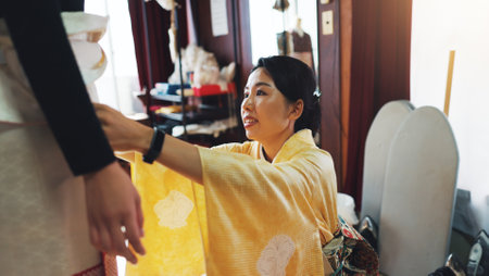Asian woman, dress and fashion designer with waist size for tailoring, garment or clothing design at boutique. Japan, female people or seamstress with customer for belt, outfit or kimono at shopの写真素材