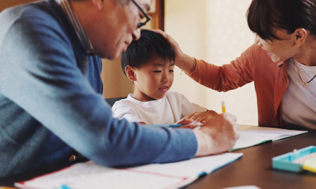 Homework, family and help with boy, books and education with knowledge, studying and writing. Apartment, mother and father with ideas, child development and support with growth, learning and Japanの写真素材