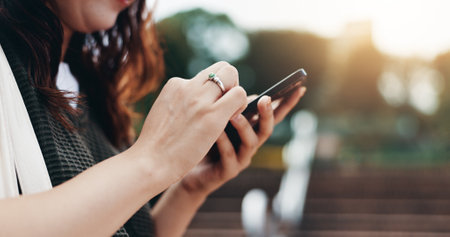 Woman, phone and outdoor hands at university, student texting and online for assignment. Person, campus park and college website for module learning, education and course for knowledge in Japanの写真素材