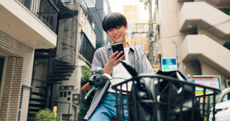 Phone, bicycle and smile with Japanese man in city for location, digital map and travel. Social media, cycling and mobile app with person and bike in japan for networking, connection and adventureの写真素材