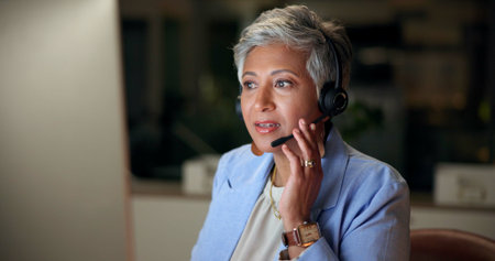 Call center, headset and mature woman listening, telemarketing or help desk at night in office....