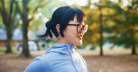 Japan, runner and woman in park, fitness and smile with nature, wellness and training routine. Asian...