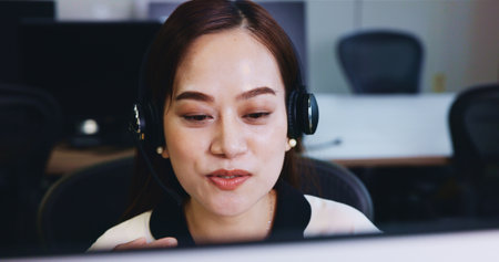 Call center, headset and Japanese woman in agency for customer service, technical support or advice. Female person, microphone and telecommunication with consulting, talking or feedback for help deskの写真素材