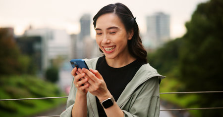 Cellphone, sports and woman outdoor with online exercise plan for running, wellness and training. Happy, fitness and Japanese female athlete on phone with mobile health tracker app for cardio workoutの写真素材