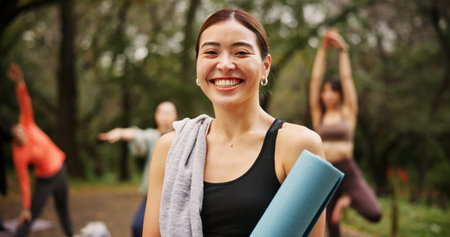 Park, woman and happy on portrait for yoga session with mat for health, self care and wellbeing in Japan. Female person, outdoor and smile or satisfied in confidence for fitness, workout and exerciseの写真素材