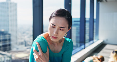 Fitness, health and shoulder pain with Japanese woman at gym for recovery or rehabilitation. Exercise, injury and wellness with athlete massaging joint for relief from discomfort or strain in Japanの写真素材