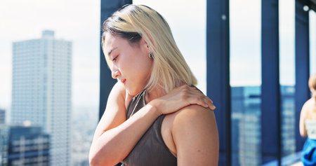 Exercise, injury and shoulder pain with Japanese woman at gym for recovery or rehabilitation. Fitness, health and wellness with athlete massaging joint for relief from discomfort or strain in Japanの写真素材