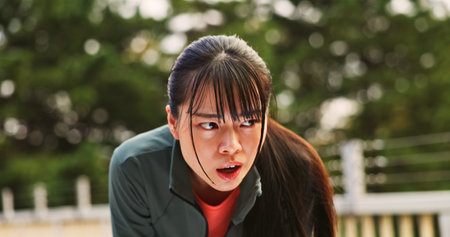 Fatigue, woman and rest for running in city of sport exercise, workout recovery and breathing. Athlete, tired and relaxing with break of cardio performance, fitness training and sweat on Japan bridgeの写真素材