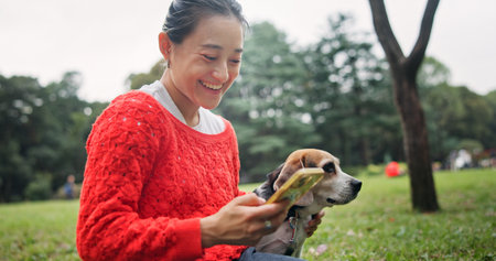 Nature, phone and woman with dog in forest for bonding, companion and love for adoption. Happy, connection and Japanese female person with beagle puppy for pet outdoor in woods for playing together.の写真素材