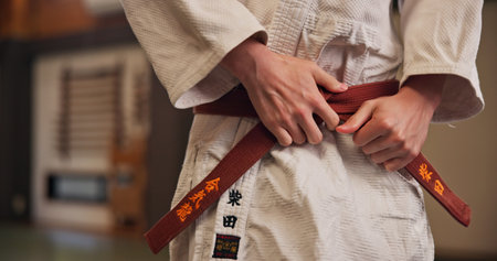 Person, hands and red belt for karate with exercise, ready and prepare for training in Japan studio. Man, martial arts and professional fighter in dojo for sport, expertise and sensei in self defenseの写真素材