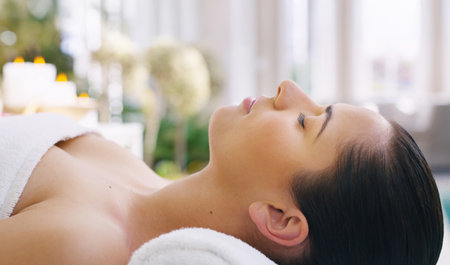 Massage, relax and wellness with woman in spa for luxury treatment, peace or stress relief. Break, satisfaction and therapy with customer on bed or table in salon for getaway, holiday or vacationの写真素材
