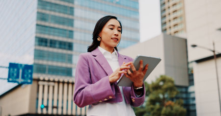 Business, japanese woman and tablet by buildings for online listing, residential development and networking. Professional, real estate agent and digital app for research, web information and internetの写真素材