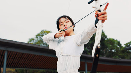 Serious, training and woman with bow, aim and preparing for competition, equipment or outdoor for game. Contest, athlete and practice from tournament, skills and challenge for person, archer or Japanの写真素材