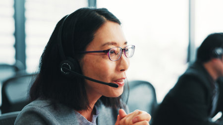 Woman, telemarketing operator and customer support agent in office, talking and advisor to client. Female person, call centre representative and helping consumer with loan in Japan insurance agencyの写真素材