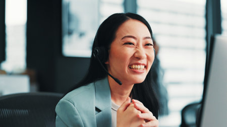 Woman, laughing and customer support agent in office, funny joke and advisor to client. Female person, call centre representative and help consumer with loan, Japan and computer at insurance agencyの写真素材