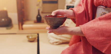 Hands, guest and drink with bowl, chawan and traditional kimono for tea ceremony. Japanese ritual, spirituality and mindfulness with cultural outfit for herbal matcha, respect and home hospitalityの写真素材