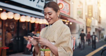 Street, travel and woman in kimono with phone, smile and online search for location on city map. Smartphone, scroll and happy Japanese girl in traditional fashion with mobile app for urban navigationの写真素材