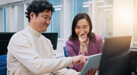 Laughing, pointing and tablet with business women in office for creative, design or web development. Collaboration, feedback or funny with Japanese man and woman in workplace for online reviewの写真素材