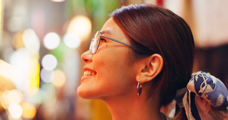Asian woman, face and night with smile in city for travel, sightseeing or tourism on bokeh. Japan, tourist or profile of happy female person with joy for holiday destination or vacation trip in Tokyoの写真素材