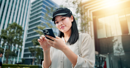 Travel, typing and woman with smartphone, city and communication with job opportunity and research. Outdoor, walking and Asian person with mobile for chat, smile and planning for internship and Japanの写真素材