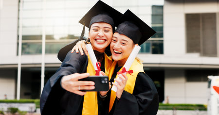 Women, university student and happy on graduation with selfie for social media or profile picture in Japan. People, campus and smile with scroll for memories, success and achievement as friendsの写真素材