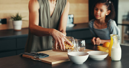 Hands, child and mother with breakfast cereal, hungry and cooking for health in home. Mom, kid and prepare food in kitchen, help and parent pouring organic morning meal for nutrition, diet and growthの写真素材
