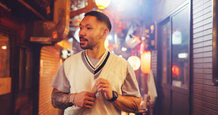 Night, street market and culture with Japanese man in city on vacation for shopping, travel destination or festival. Search, traditional holiday and walking with person for urban, tourism or heritageの写真素材