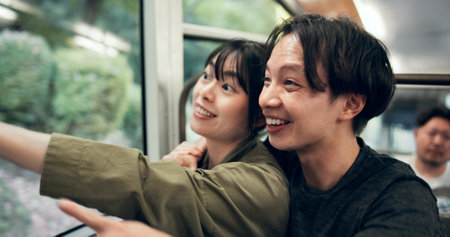 Vacation, couple and travel in cable car for tourism, holiday and pointing for sightseeing in Japan. Smile, man and woman in transport for adventure, hug and trip together on journey to Mount Takaoの写真素材