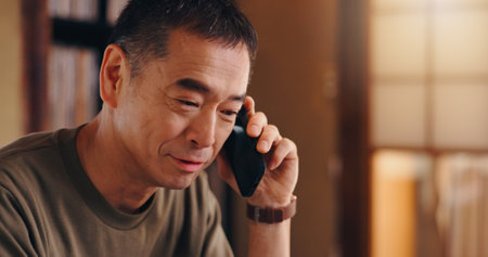 Japanese, man and home with phone call for communication, listening and banking service for account. House, mature person or assistance with mobile conversation for financial enquire, invest or smileの写真素材